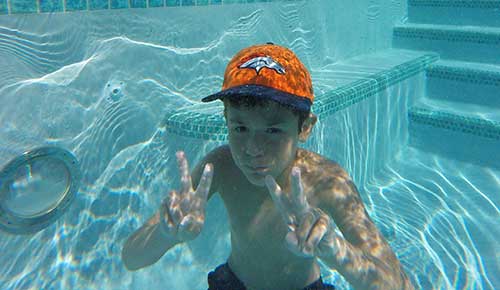 Kid with Broncos hat enjoying pool